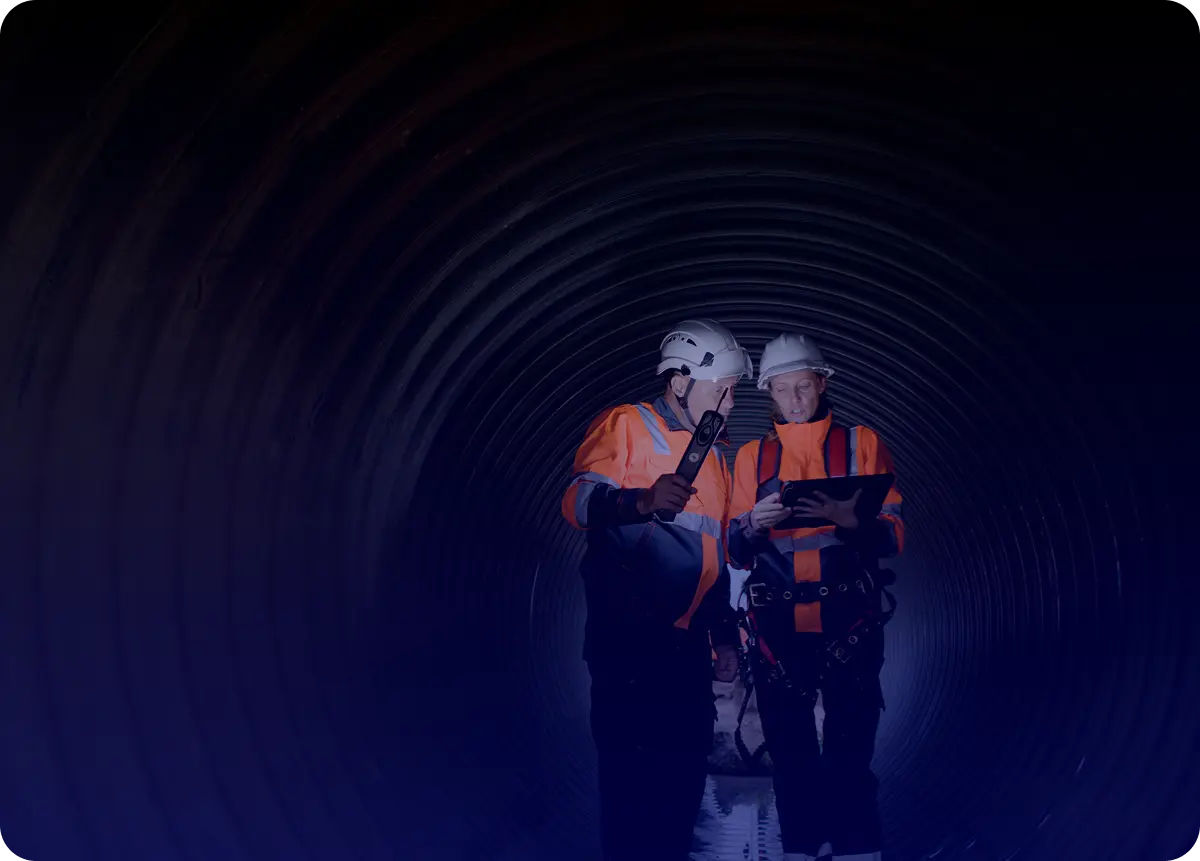 Two figures in orange outfits inside a dark tunnel.