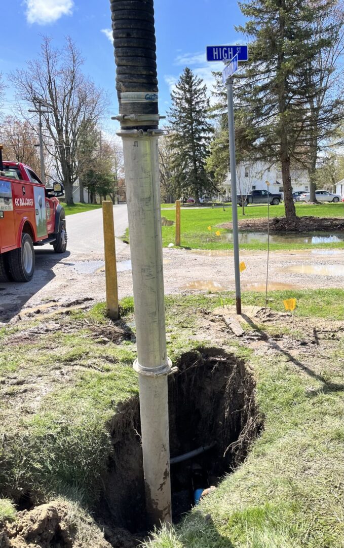 A large hole dug around a utility pole with a vehicle nearby.