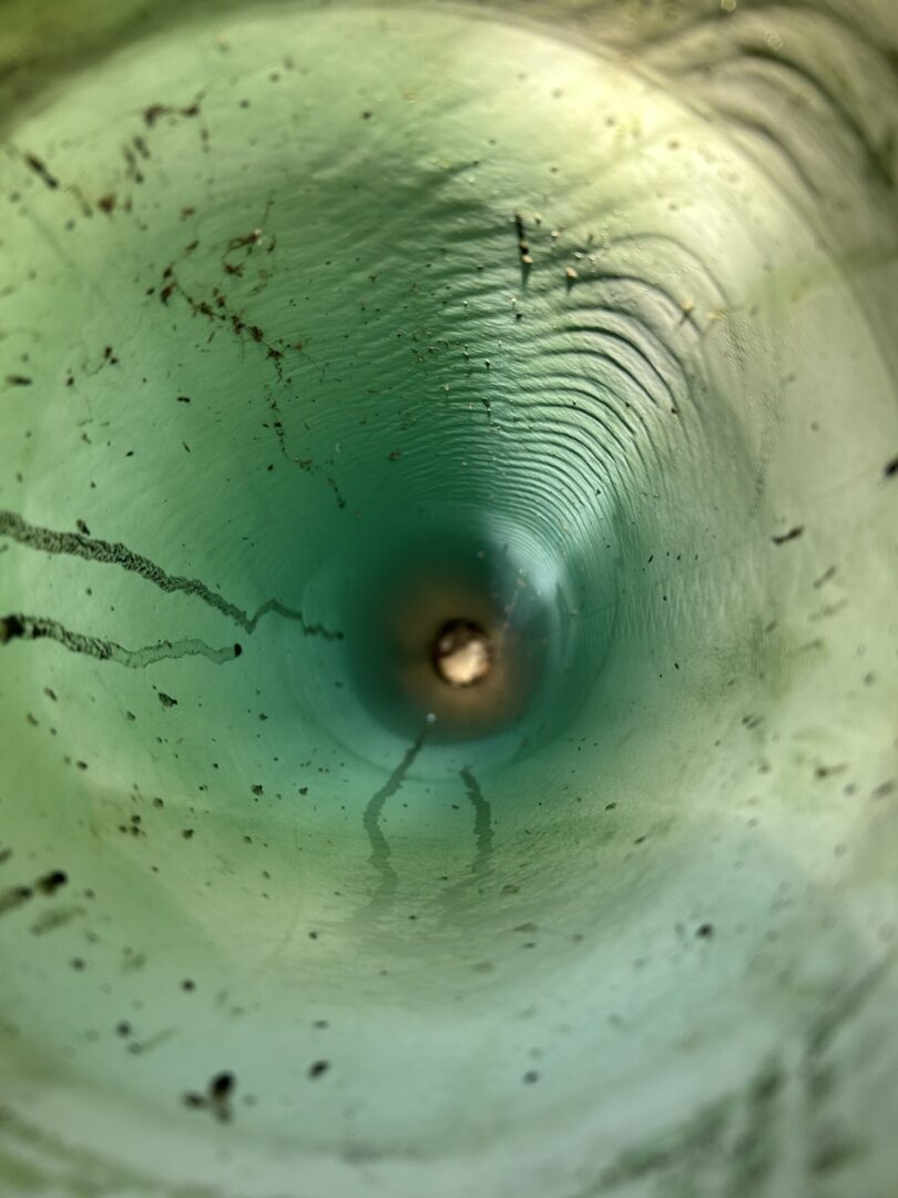 View down the inside of a deep, greenish cylindrical tunnel.