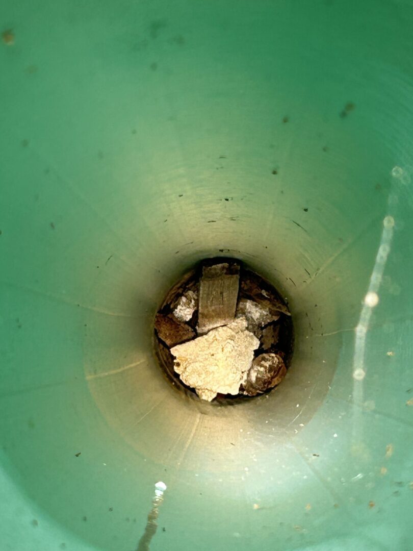View inside a teal-colored cylindrical pipe with debris at the bottom.