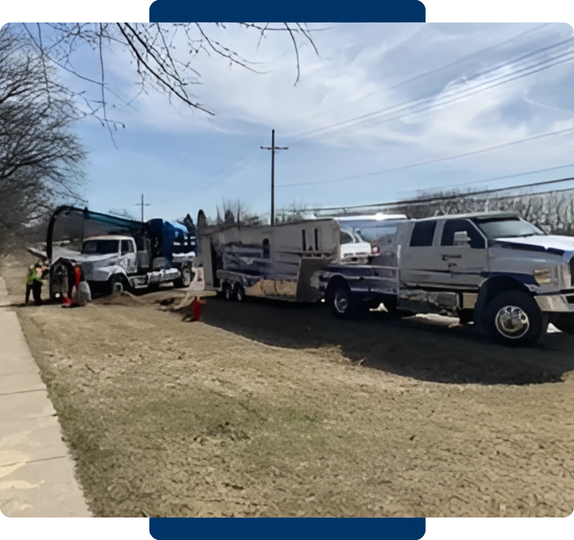 Two pickup trucks towing campers parked on a roadside with a person nearby.