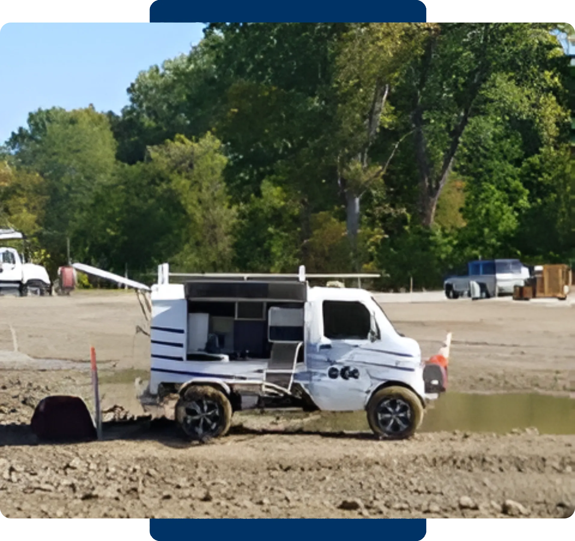 Small white utility truck parked on a dirt road near trees.