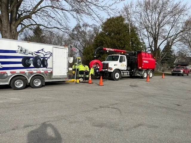 Workers in high-visibility gear repairing a red truck on a roadside.
